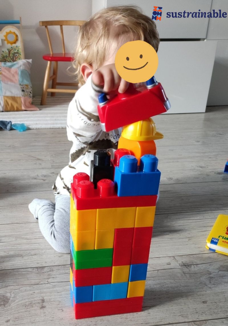 Klein kind stapelt geconcentreerd gekleurde blokken tot een hoge toren