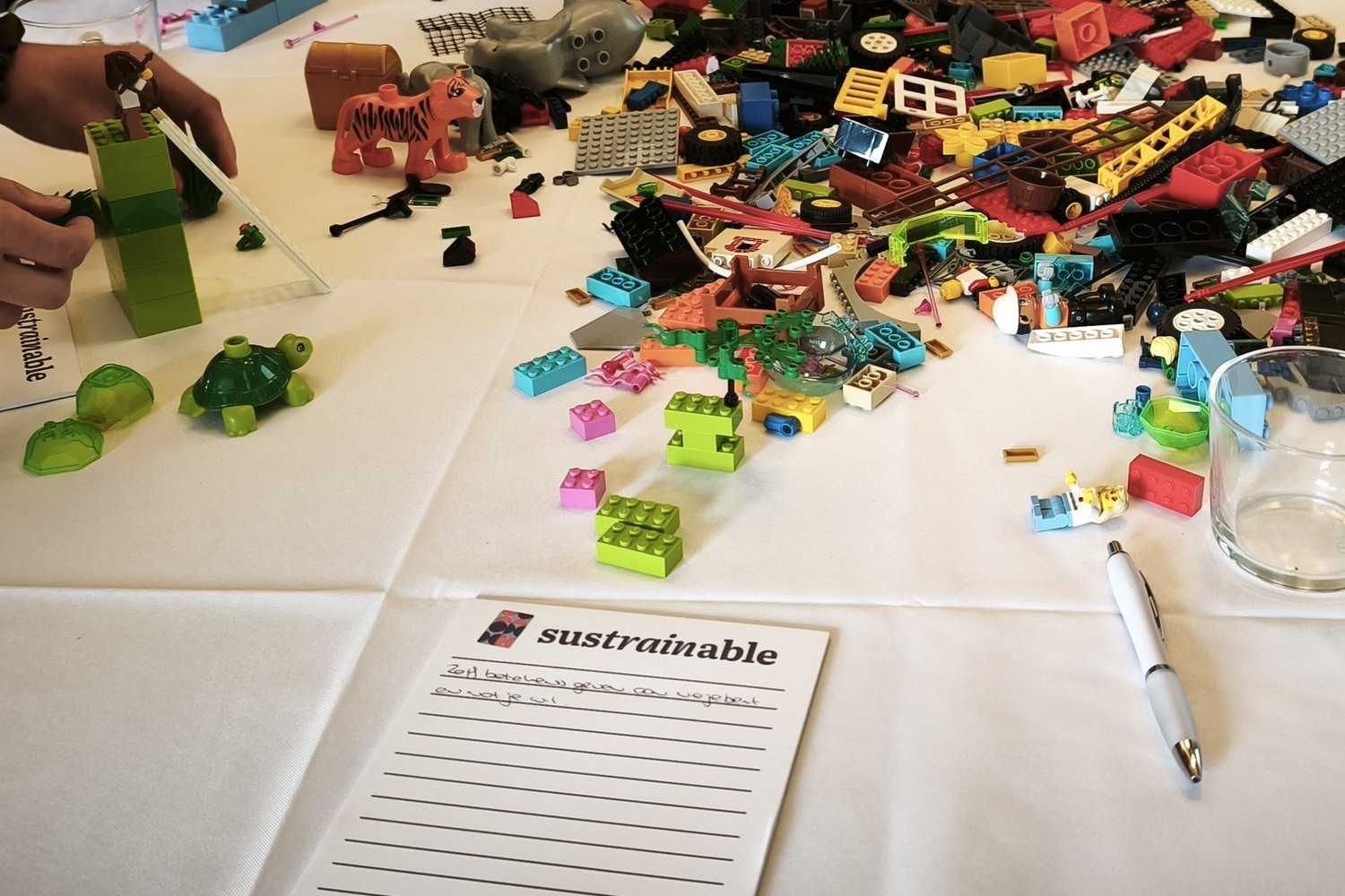 Werktafel tijdens een Sustrainable-werksessie met bouwmateriaal en notities.